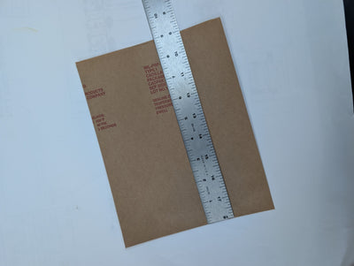 Brown paper bag with a ruler for measurement on a white background